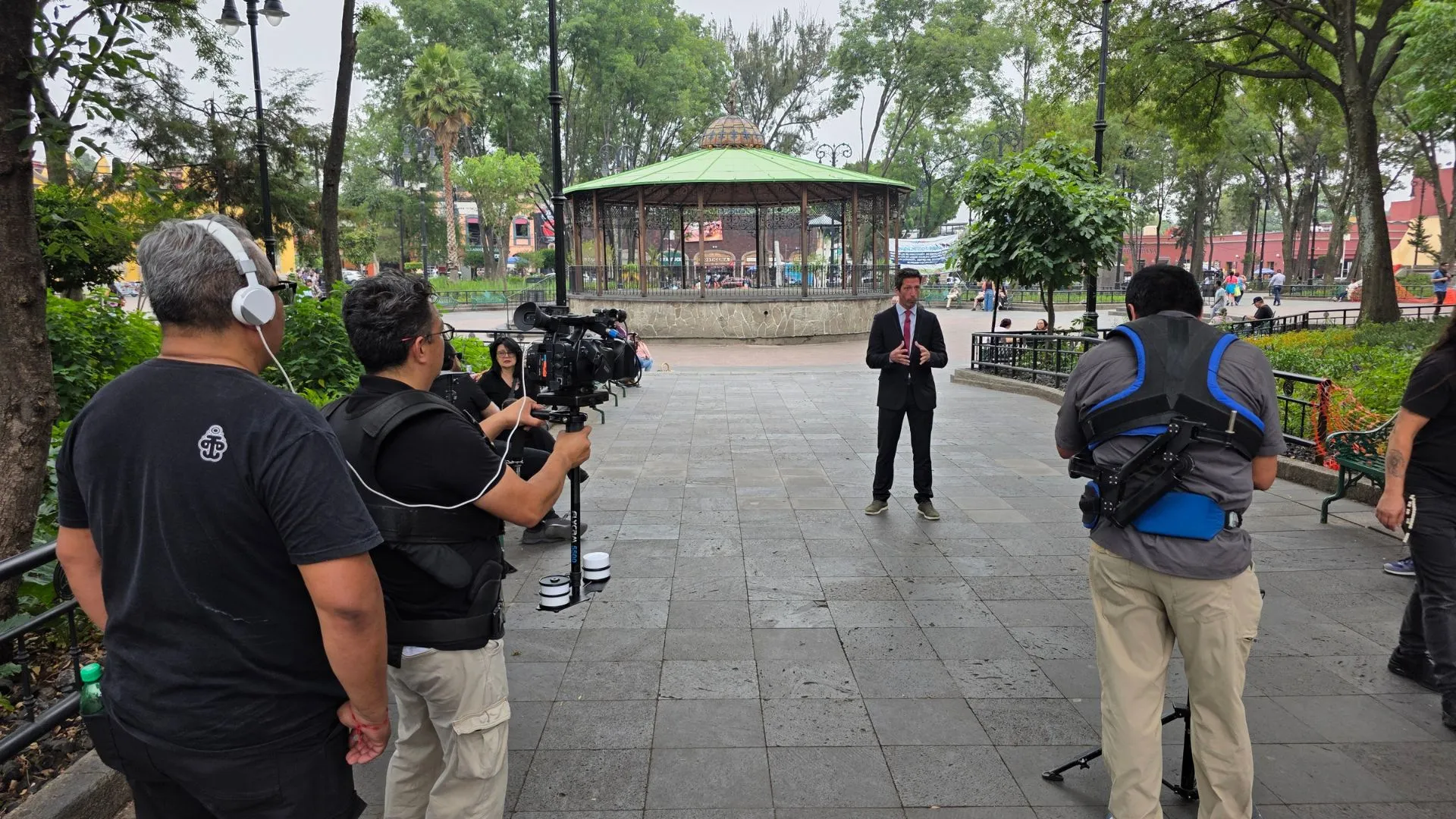 Crew filming an outdoor interview in Jardín Hidalgo, Coyoacán, for Expertise France's Rendez-Vous de l'Expertise.