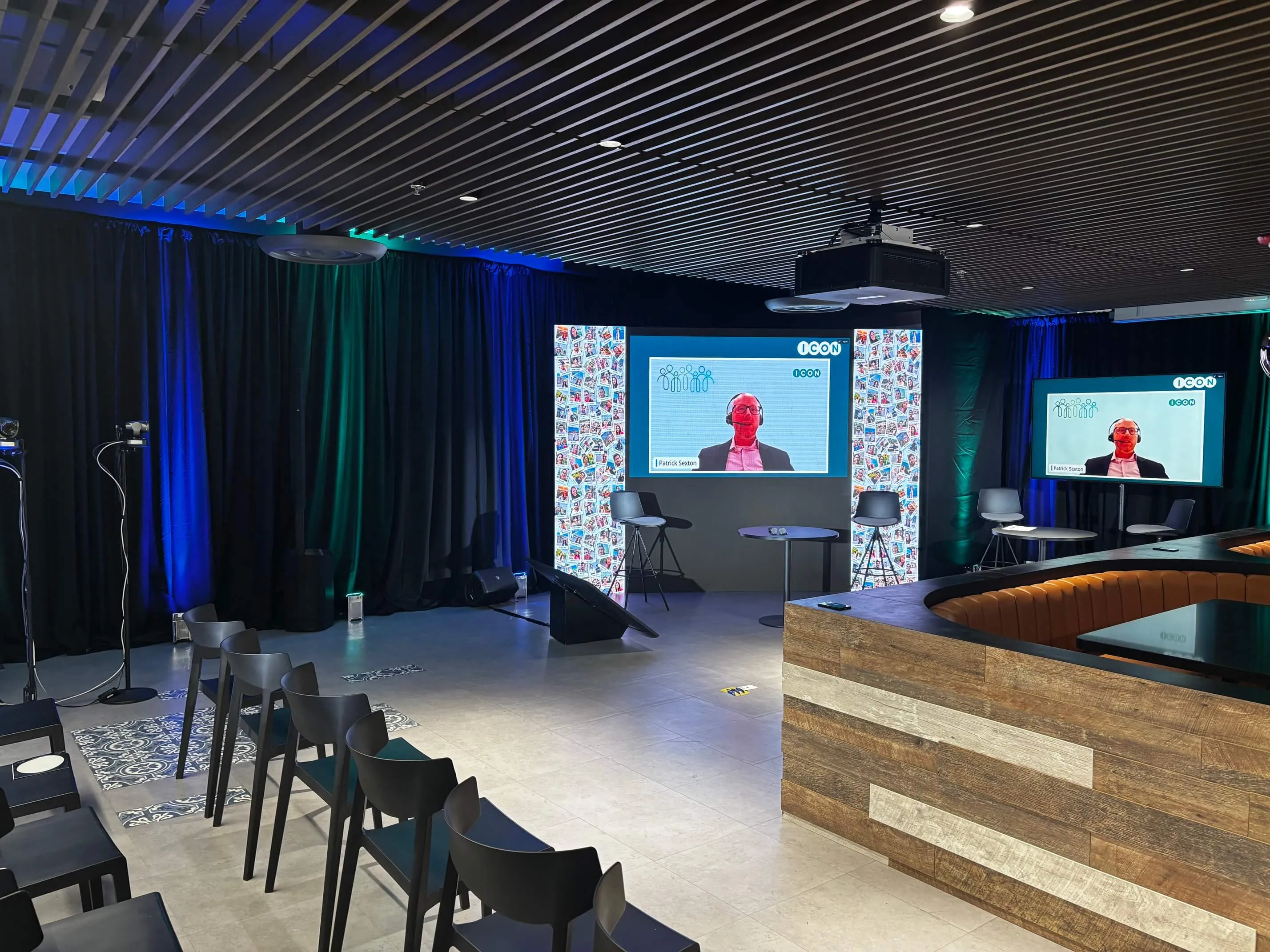 ICON cafeteria presentation area with an LED backdrop and a display showing a remote contributor from the Zoom studio.
