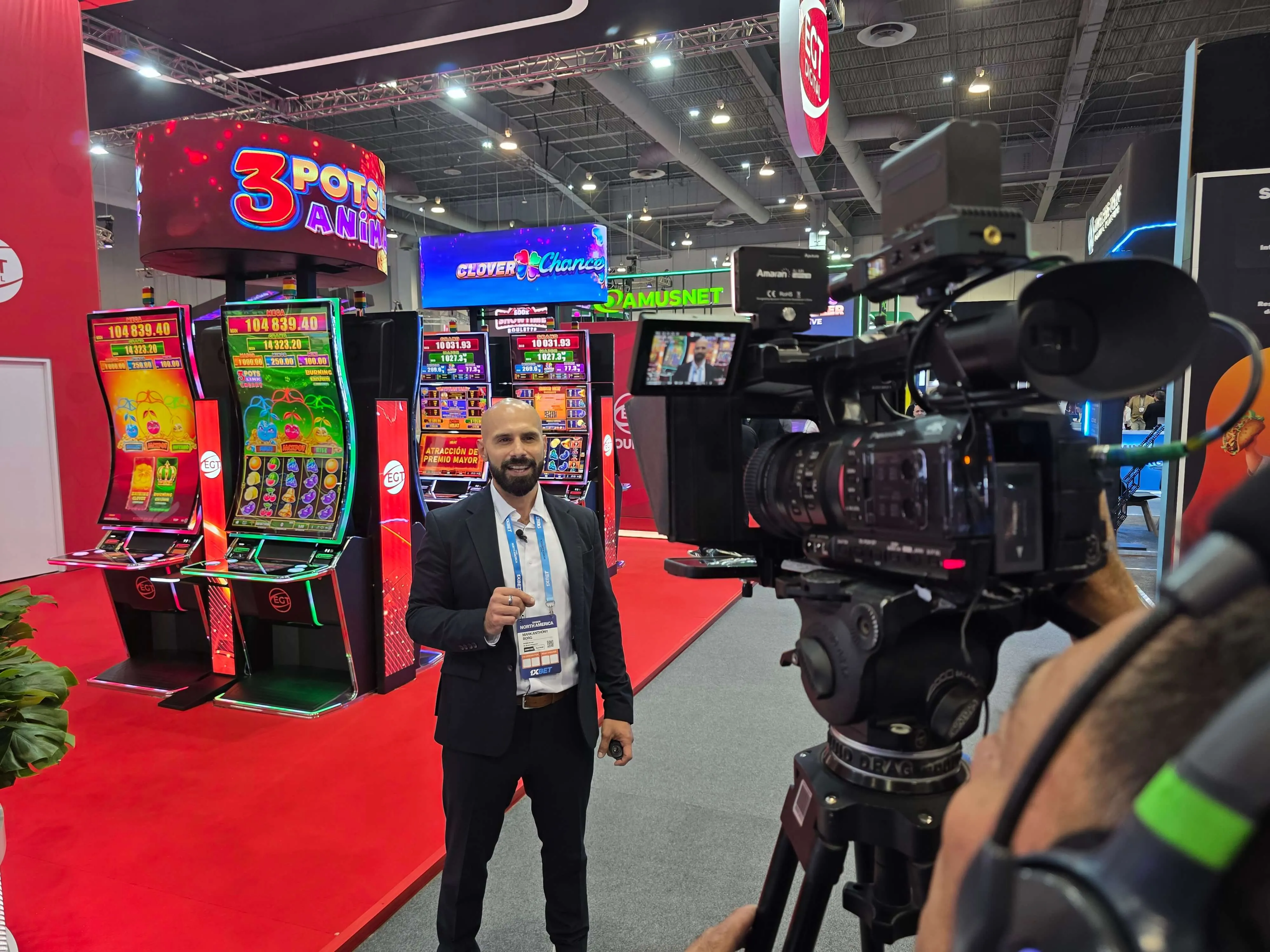 Camera operator recording an interview on the SiGMA North America 2026 exhibition floor.
